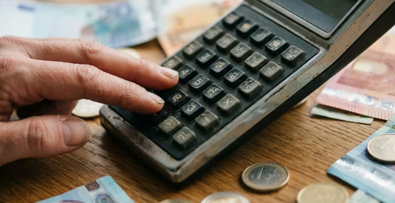 Main calculant des économies avec factures et calculatrice sur table en bois