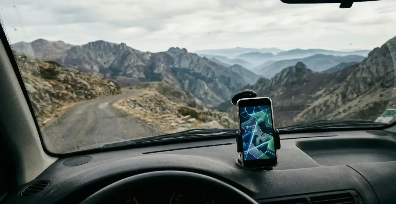 Vue intérieure d'une voiture avec smartphone montrant une carte téléchargée dans une zone montagneuse sans réseau