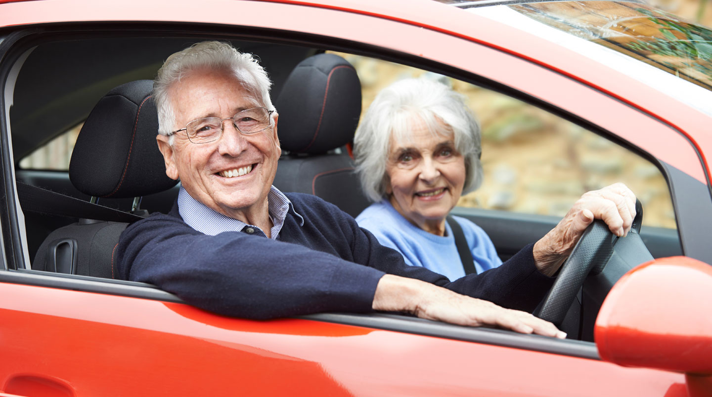 Couple de retraités français devant leur maison avec petite voiture garée dans l'allée